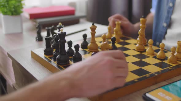 Two Young Men Playing Chess at Home in the Living Room