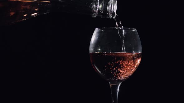 Pouring Pink Champagne From Bottle Into Glass. Black Background