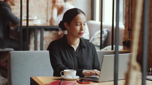 Brunette Business Lady Using Laptop and Posing for Camera in Cafe