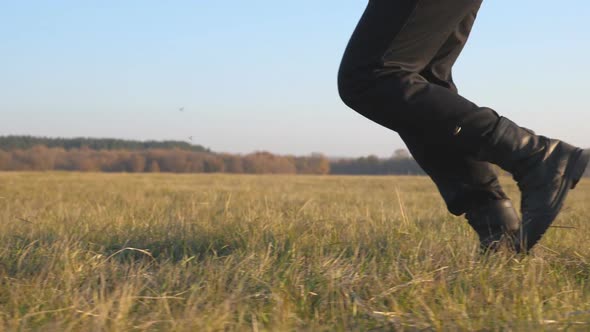 Feet of Soldier in Black Boots Run Across Field and Stepping on Dry Grass