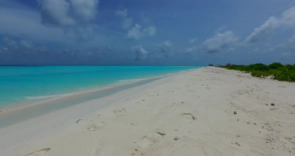 Wide angle flying tourism shot of a summer white paradise sand beach and turquoise sea background in