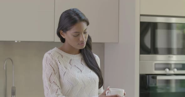 Woman smelling and drinking coffee in kitchen