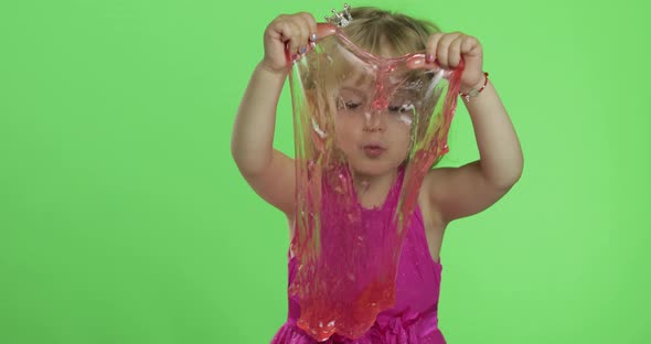 Child Having Fun Making Red Slime. Kid Playing with Hand Made Toy Slime