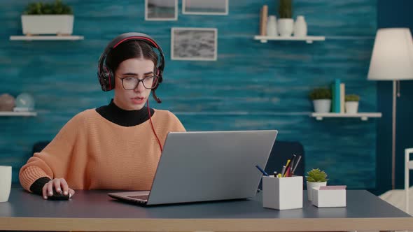 Young Person Talking on Online Videoconference with Headphones alt