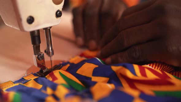 African happy tailor working with sewing machine
