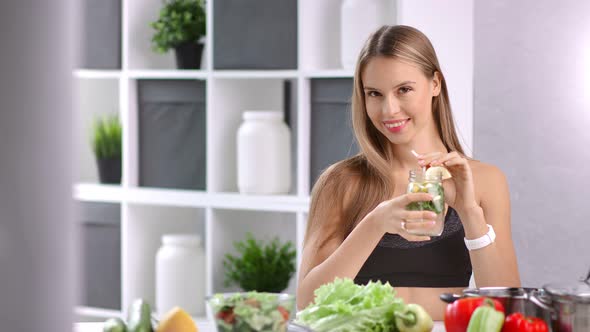 Beautiful Dieting Woman Smiling Posing with Healthy Cocktail with Mint and Lemon in Kitchen