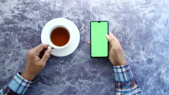 Top View of Man Hand Using Smart Phone and Drinking Tea