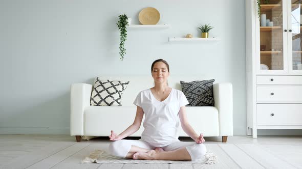 Tranquil Pregnant Woman Meditates in Lotus Pose at Home