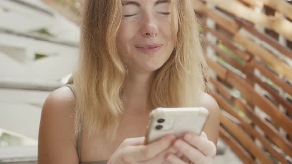 A Pretty Young Woman with Vitiligo Pigmentation Sits on the Stairs Chatting on the Phone