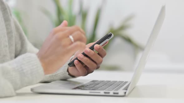 Close Up of Hands of African Woman with Laptop Using Smartphone