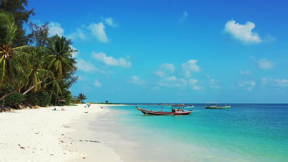 Tropical island beach background. White sand, boats, and palms leaning over the coast.