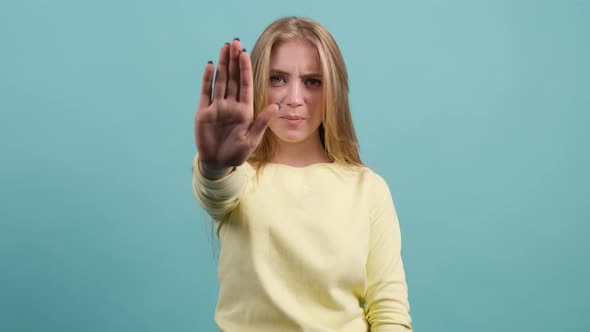 Close Up of Young Woman Making Stop Gesture with Her Hand Isolated on a Turquoise Background