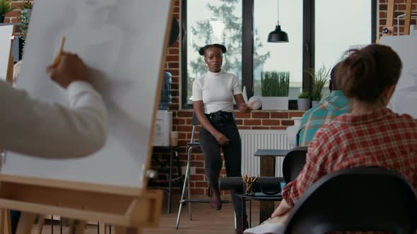 African American Woman Showing Vase Model to Students in Art Class