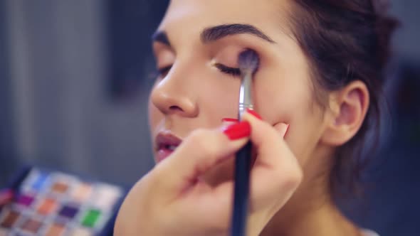 Professional Makeup Artist Applying Eyeshadow to Model Eye Using Special Brush