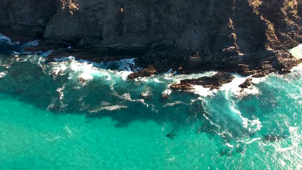 Aerial view of waves crashing into ocean rocks