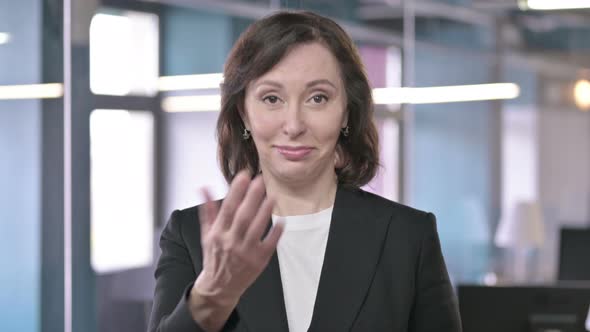 Portrait of Cheerful Middle Aged Businesswoman Pointing Finger at the Camera and Inviting