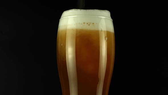 Rotate the light beer into the glass. Cold light beer in a glass with water drops