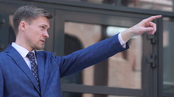 Businessman Pointing with Finger Outside Office