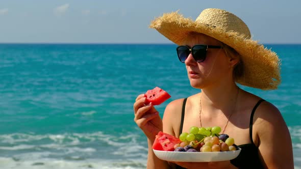 Woman on the Beach Eats Fruit