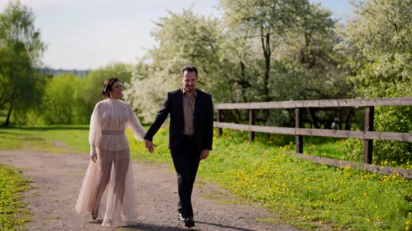 Happy Married Couple is Walking in Nature in Sunny Summer Day Adult Man and Woman are Holding Hands