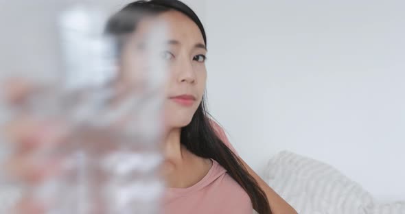 Woman drinking glass of water on bed 