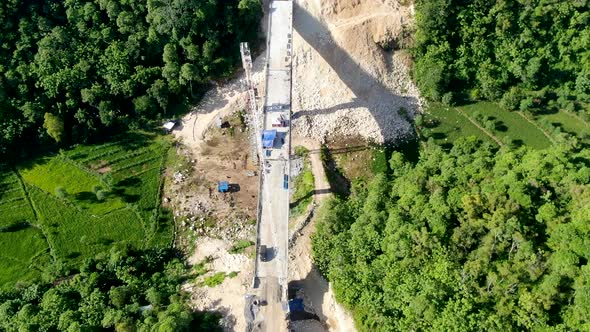 Workers building bridge over valley in forestry landscape, aerial drone view