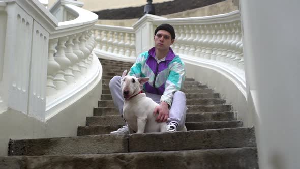 Portrait of Serious Male Animal Owner in Sportswear Petting His Purebred Bull Terrier While Sitting