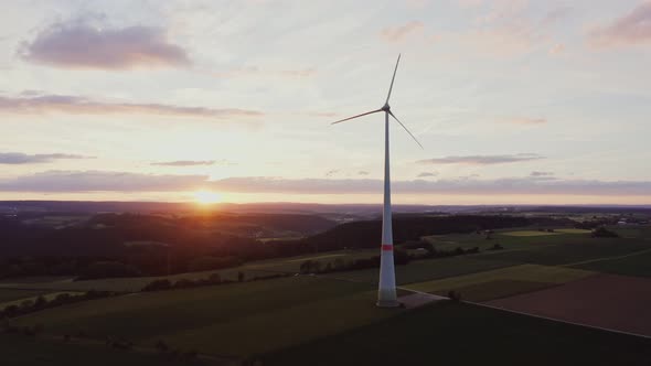 Wind Turbine in a Picturesque Green Valley in the Rays of the Setting Sun