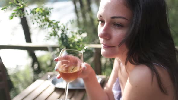 Attractive Brunette with a Glass in Her Hands Enjoying Nature in the Mountains, Sitting on the