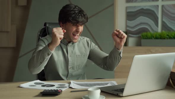 Businessman with His Hands Raised While Working on Laptop with Money Rain