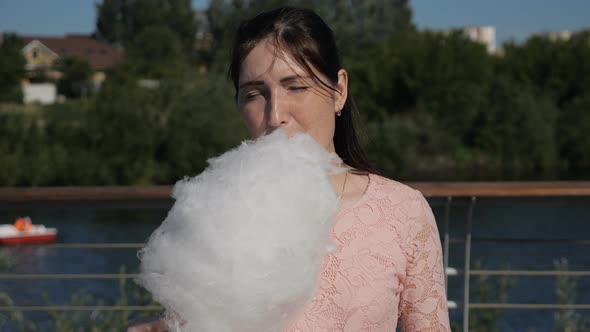 Young Woman Eating Sweet Cotton Wool Outdoors in Sunny Weather