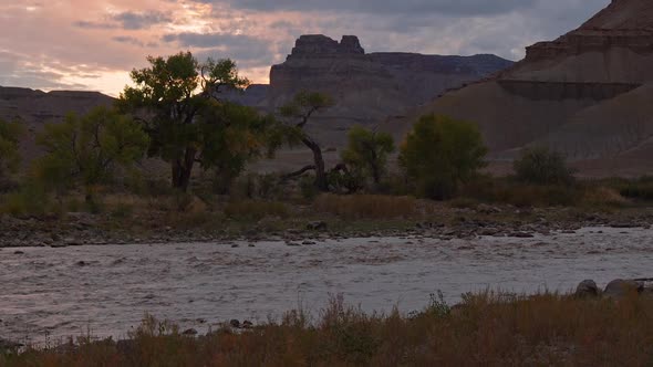 Tilt up from the Green River flowing with mud to the sky at dusk