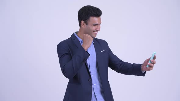 Happy Young Indian Businessman Using Phone and Looking Surprised