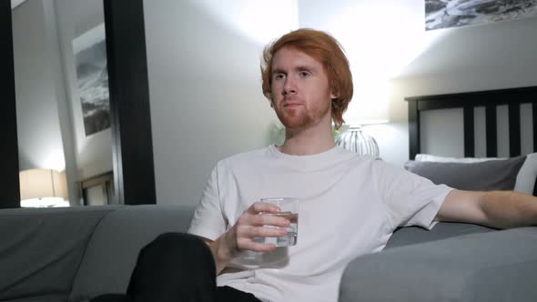 Relaxing Redhead Man Drinking Water while Sitting on Couch