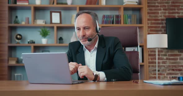Businessman in Headset Holding Videochat on Computer with His Business Partners in Modern Office