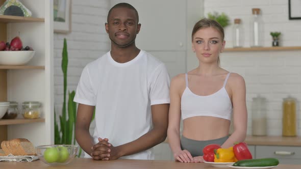 Athletic Young Woman and African Man Looking at Camera in Kitchen