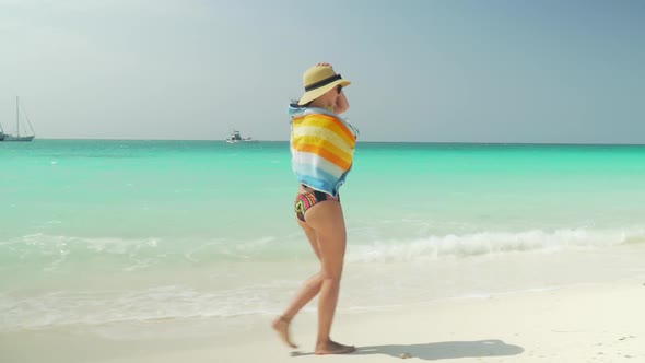 Barefoot Girl Walks On Sandy Beach Along Ocean