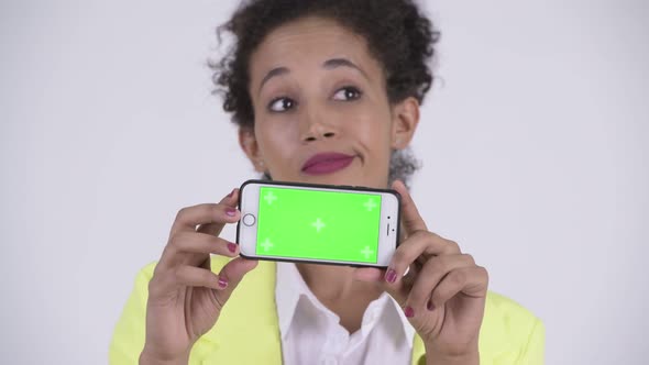 Face of Young Happy African Businesswoman Thinking While Showing Phone