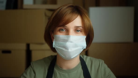 Small Business Owner Portrait of Young Woman Wearing Medical Mask on Cardboard Boxes Background
