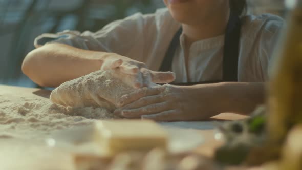 Smiling Woman Baker with Delight Sprinkles Flour on The Dough on the Table