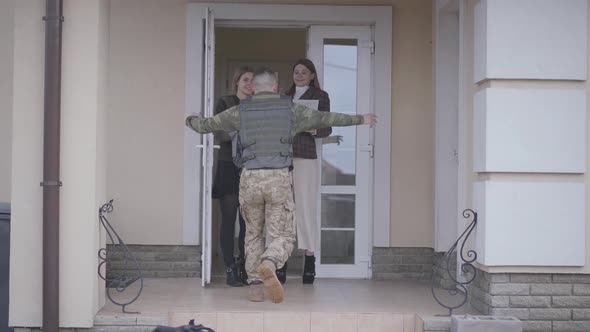 The Young Soldier in Military Closes Running To His Family, Cuddling His Sisters