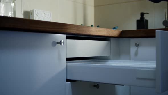 Housewife Putting Cutlery in Cupboard Drawer at Kitchen Indoors