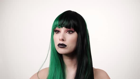 Portrait of Caucasian joyful stylish woman in black-green wig on lifht background