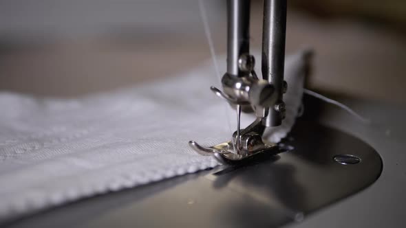 Close-up of Sewing Machine Needle with Thread Pierces Fabric in Slow Motion