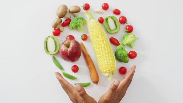 Video of biracial man's hands and fresh fruit and vegetables on white background