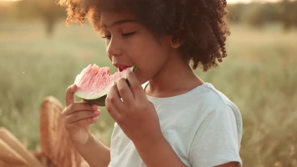 A beautiful afro-american girl is eating watermelon