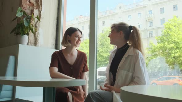 Young Girls Work Remotely in a Cafe on the Summer Terrace