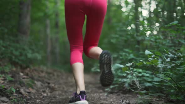 Young Woman in Red Sports Pants Running on Forest Path