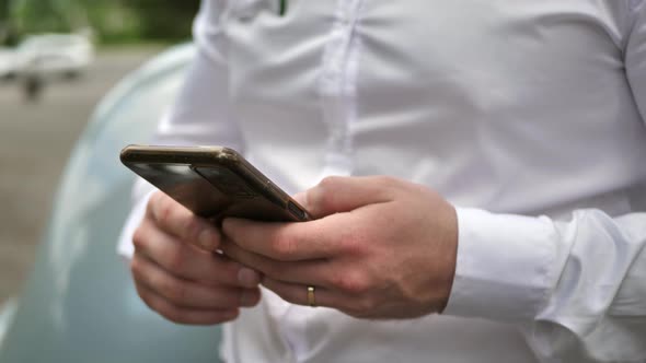 Closeup of Hands of a Young Man Typing with Fingers Using a Phone in a Mall