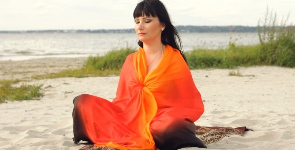 Young Woman Meditating By the Sea Long Shot